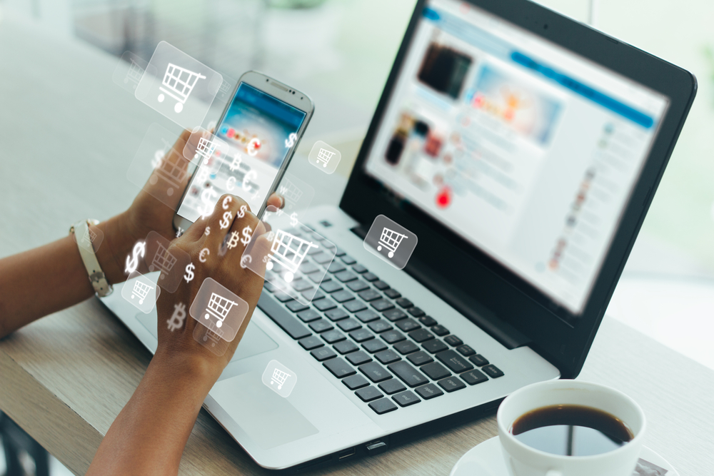 o persoană care realizează o comandă deproduse pe un magazin online de pe telefon și laptop